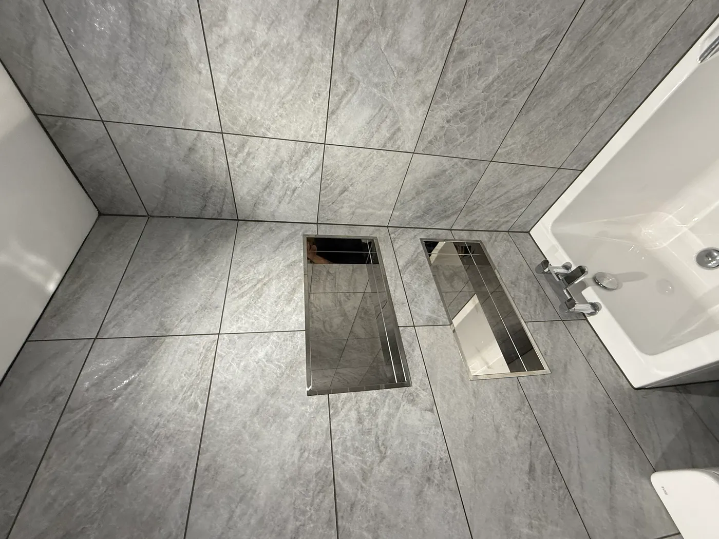 Bathroom with grey marble-effect tiles, bathtub and chrome fixtures