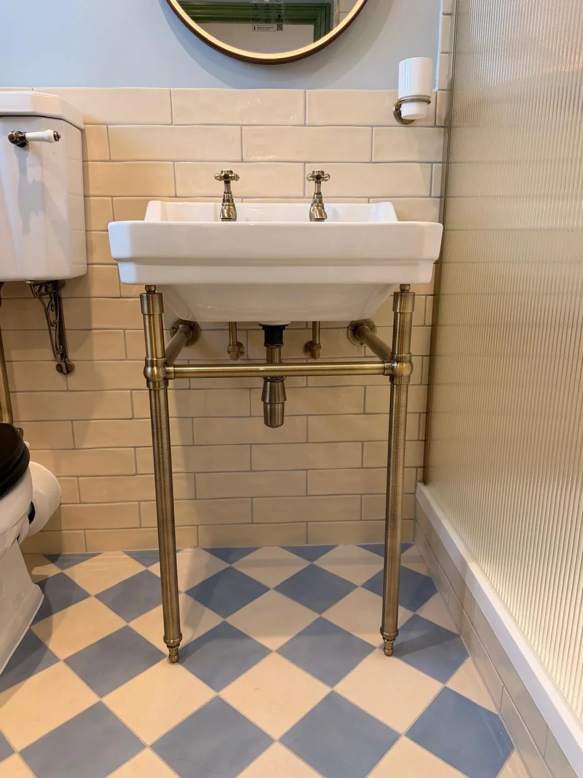 Traditional bathroom washstand with brass taps and visible pipework